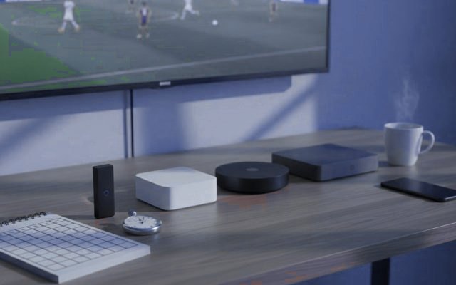 Five streaming devices, a notebook scoring grid and a stopwatch in front of a TV showing a football match